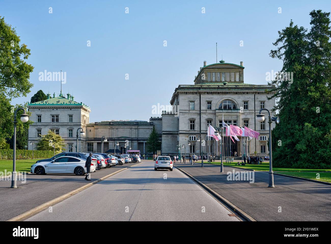 Die Villa Hügel beflagt mit rosa und weißen Flaggen mit dem Krupp Emblem. Es findet eine Veranstaltung statt die gut besucht ist. Die Flaggen wehen im Stockfoto