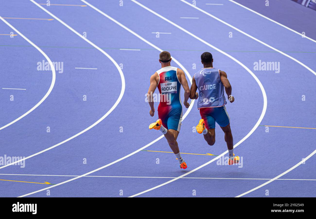 Der blinde französische Paralympic-Athlet Timothée Adolphe mit seinem Reiseleiter lief für die 400-m-Strecke im Stade de France für die Paralympischen Spiele 2024 in Paris. Stockfoto