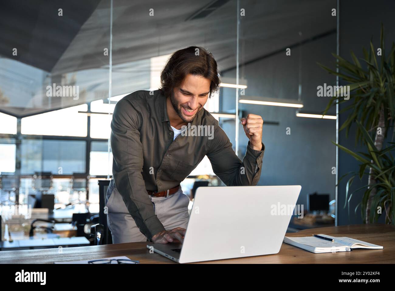 Begeisterter junger Geschäftsmann-Gewinner, der finanziellen Erfolg mit Laptop feiert. Stockfoto