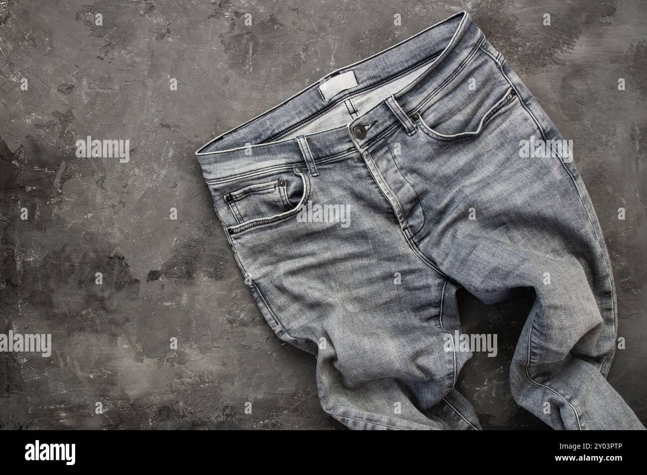 jeans aus grauem Denim, Hose auf rustikalem Steinhintergrund, Modedesign Stockfoto