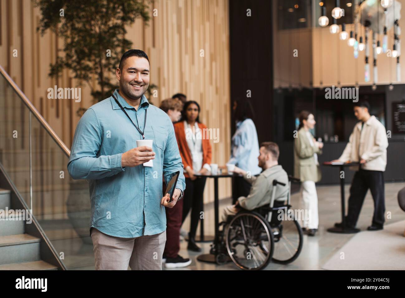 Porträt eines glücklichen männlichen Delegierten, der während der Kaffeepause im Convention Center eine Einwegtasse hält Stockfoto