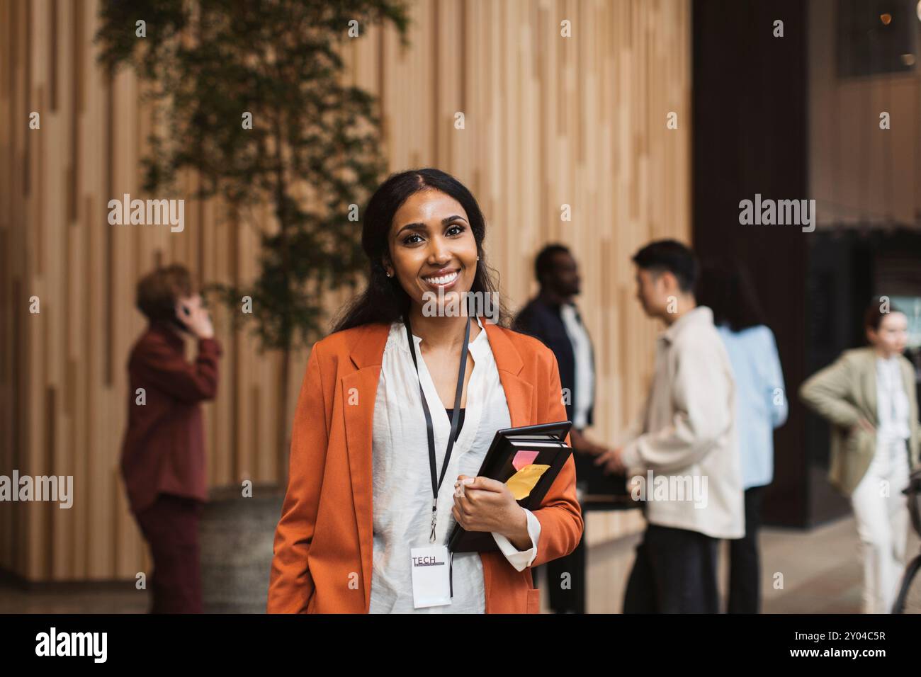 Porträt einer lächelnden Geschäftsfrau, die im Tagungs- und Veranstaltungszentrum ein Tagebuch hält Stockfoto