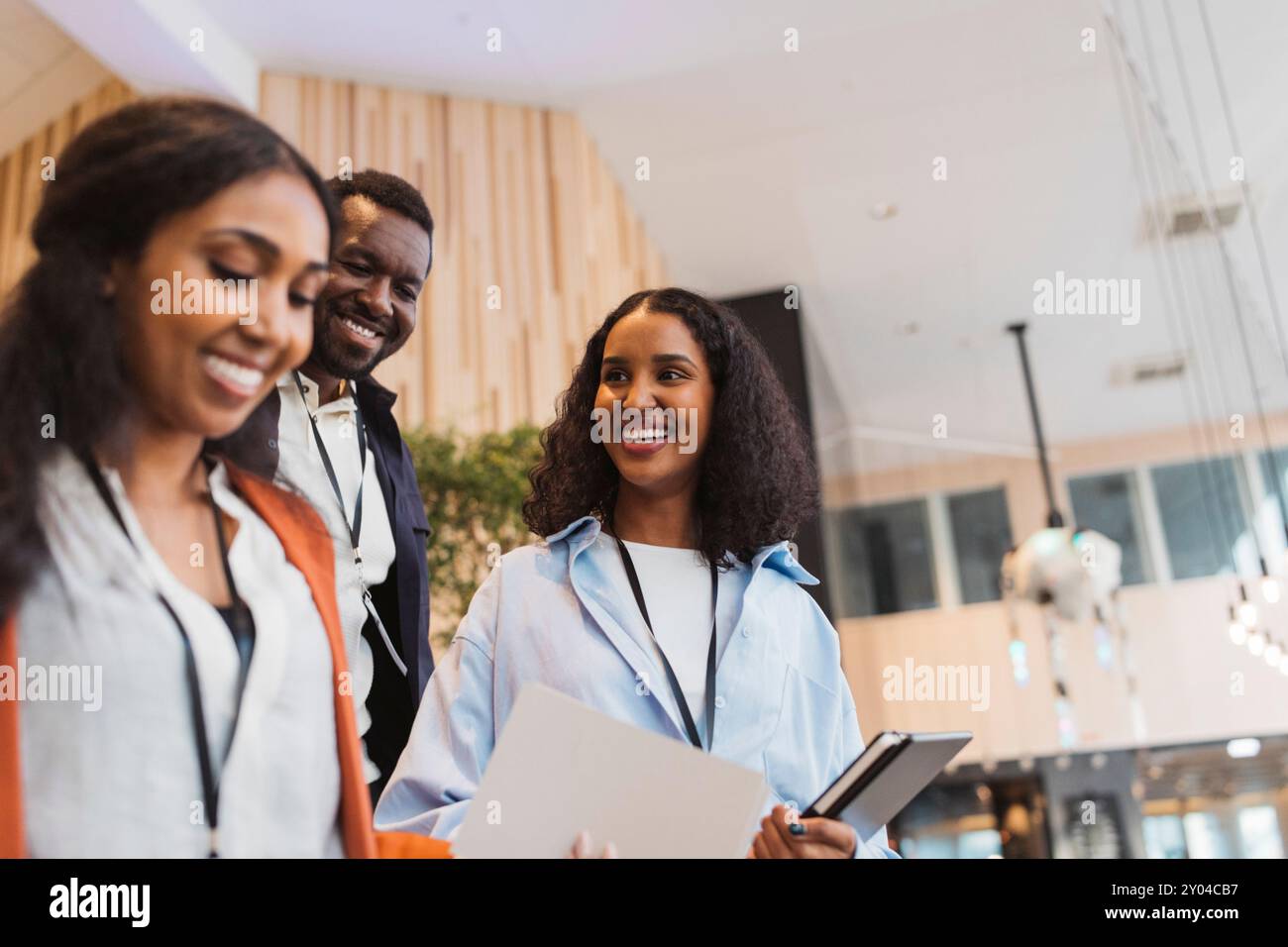 Lächelnde Unternehmerin mit männlichen und weiblichen Geschäftsleuten im Kongresszentrum Stockfoto