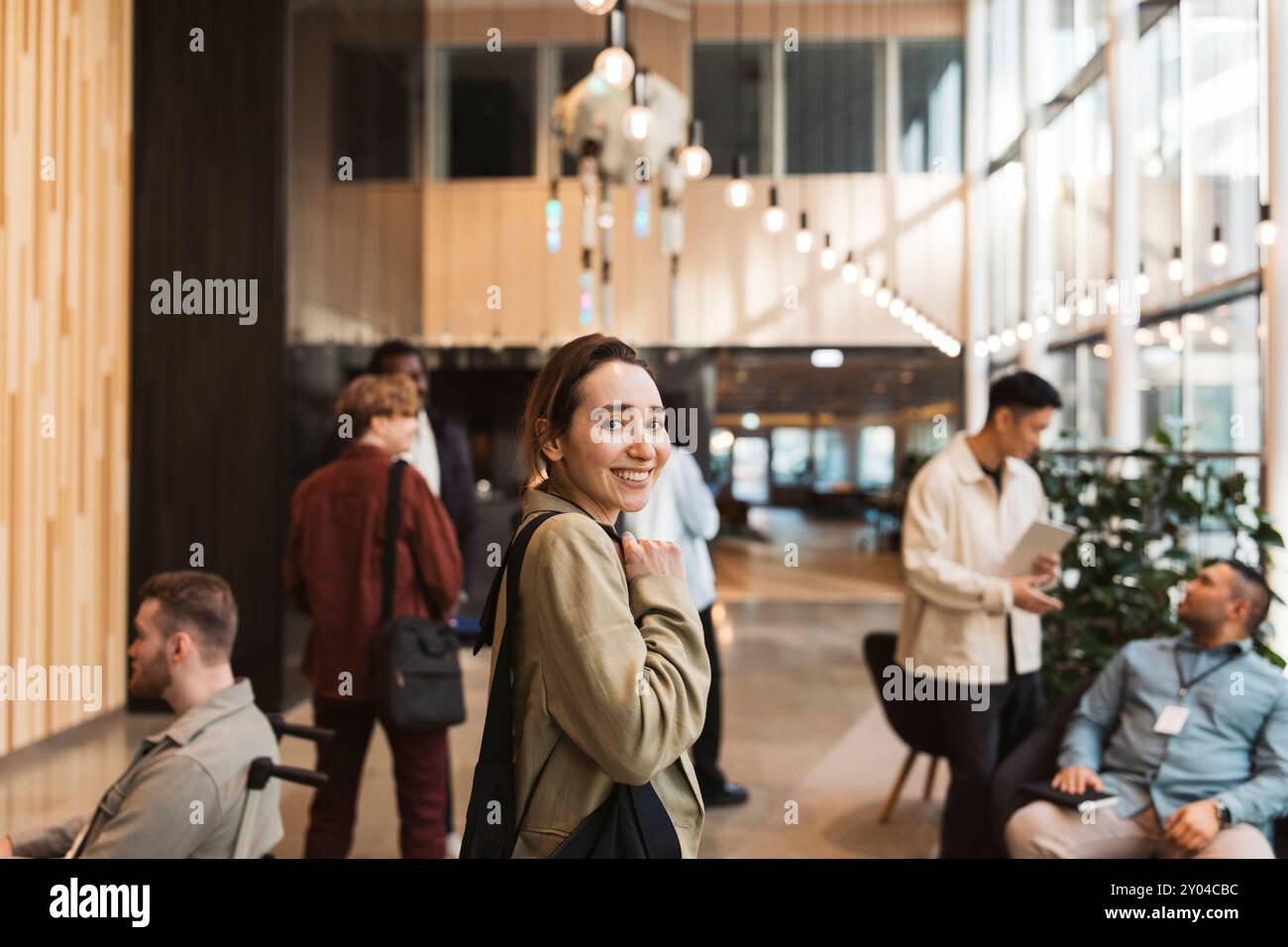 Seitliches Porträt einer lächelnden Unternehmerin, die in der Lobby des Convention Center steht Stockfoto