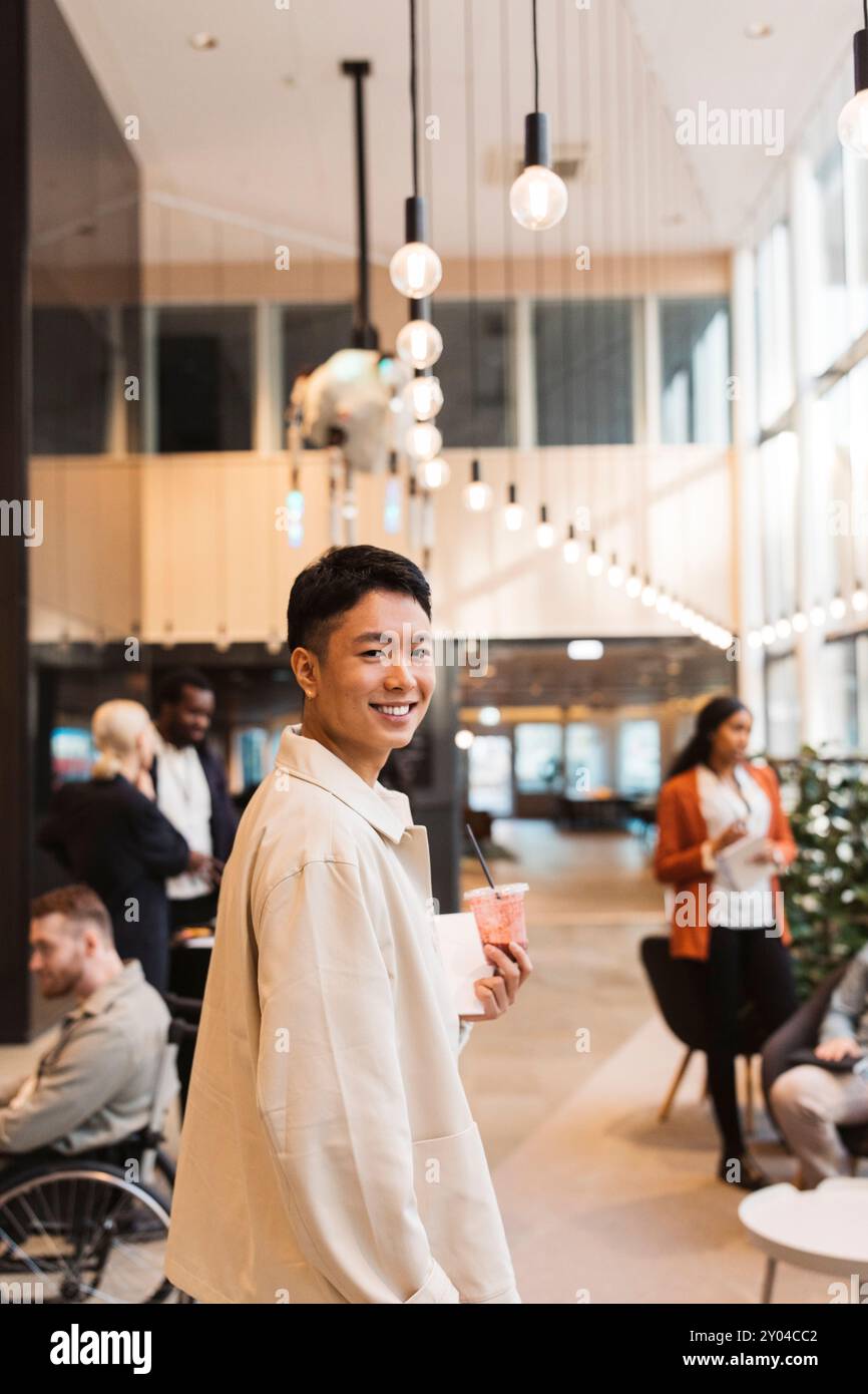 Porträt eines lächelnden männlichen Delegierten, der über die Schulter schaut, während er in der Lobby im Convention Center spaziert Stockfoto