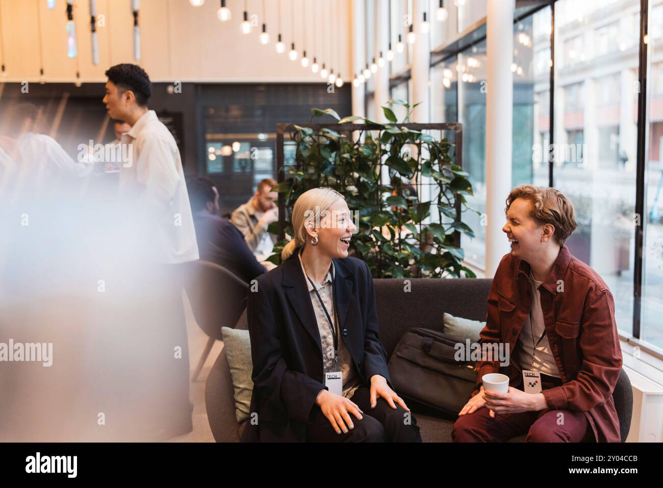 Glückliche Geschäftsleute und Geschäftsleute lachen, während sie auf dem Sofa im Tagungs- und Veranstaltungszentrum sitzen Stockfoto