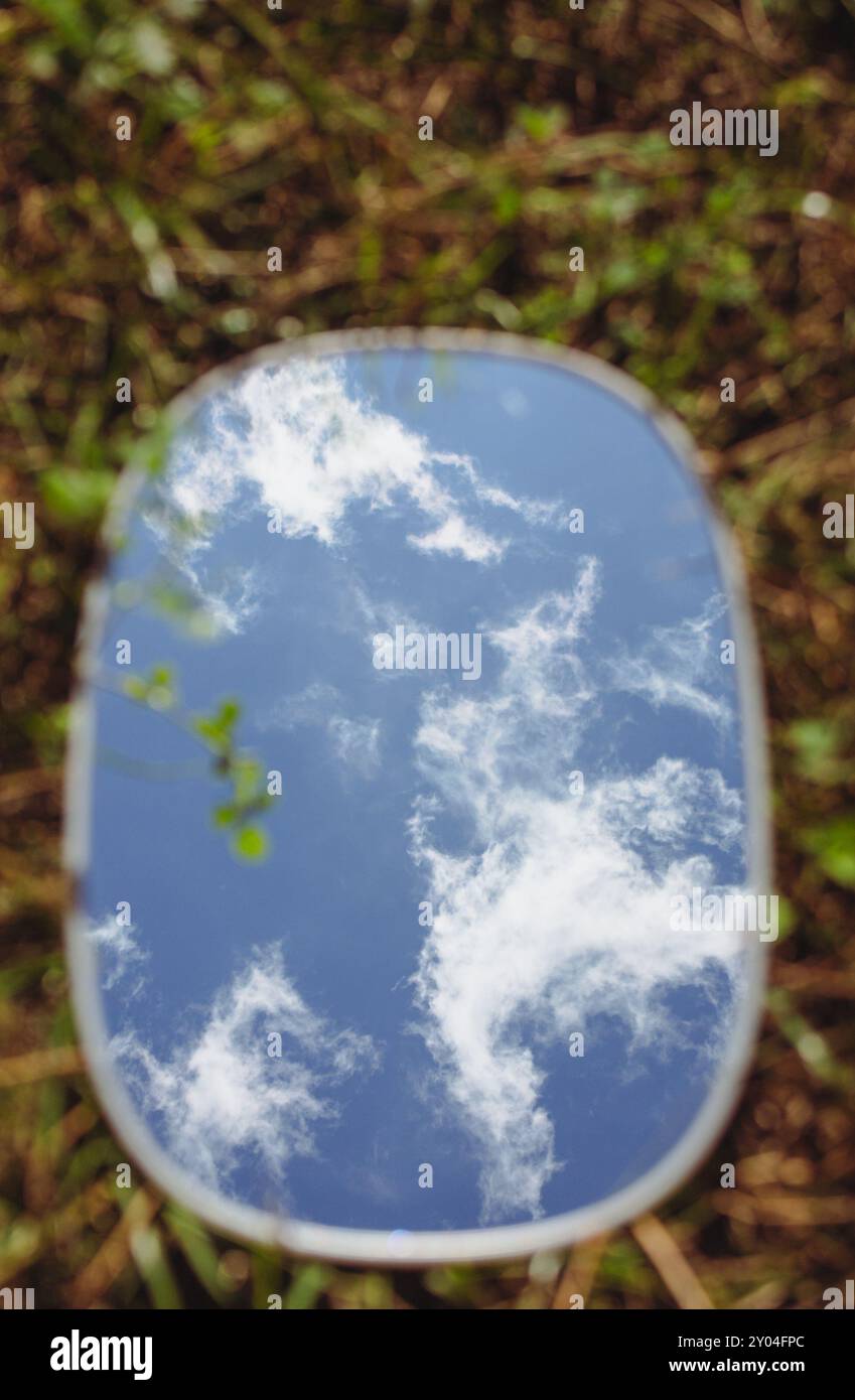 Ovaler Spiegel auf grünem Gras mit Kopierraum. Gras- und Himmelsspiegelung im Spiegel. Ökologisches Konzept. Spiegel auf grünem Rasen. Fragilität der Natur. Stockfoto