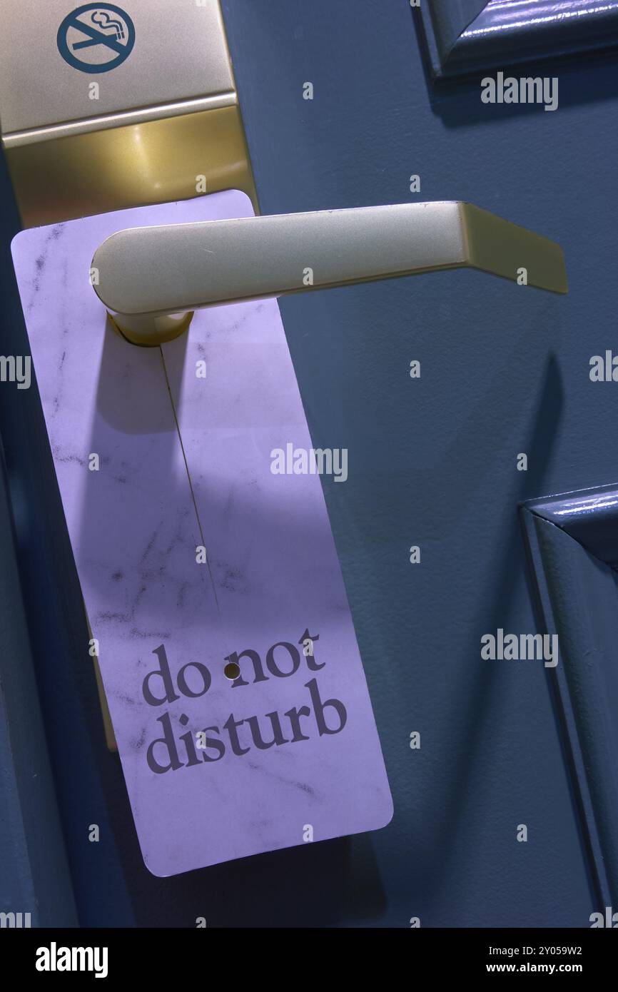 Blau lackierte Tür mit 'Do Not Disturb'-Schild und goldfarbenem Griff in einem Hotel Stockfoto