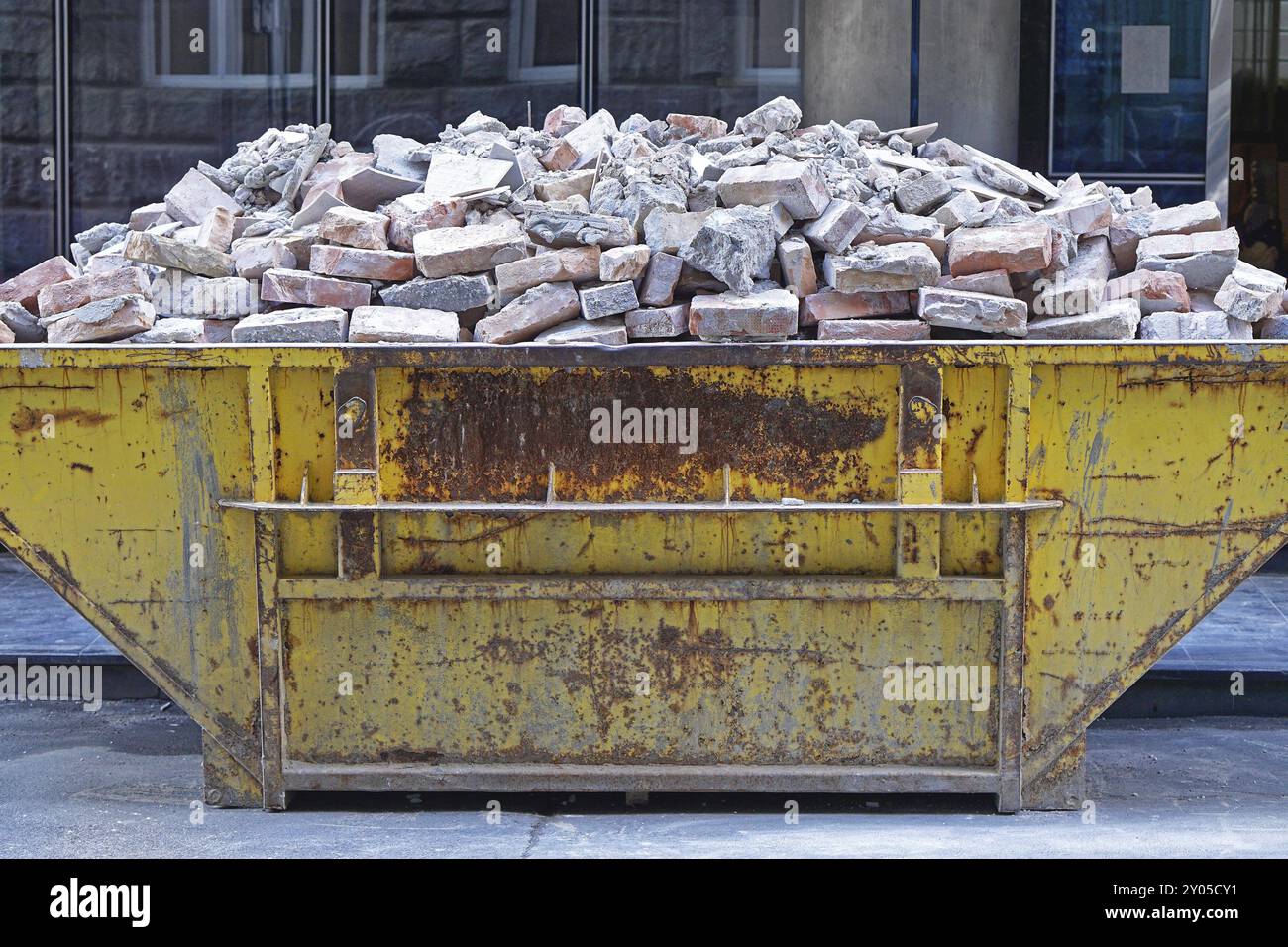 Über gefüllt überspringen Container mit Ziegel Ablagerungen Stockfoto