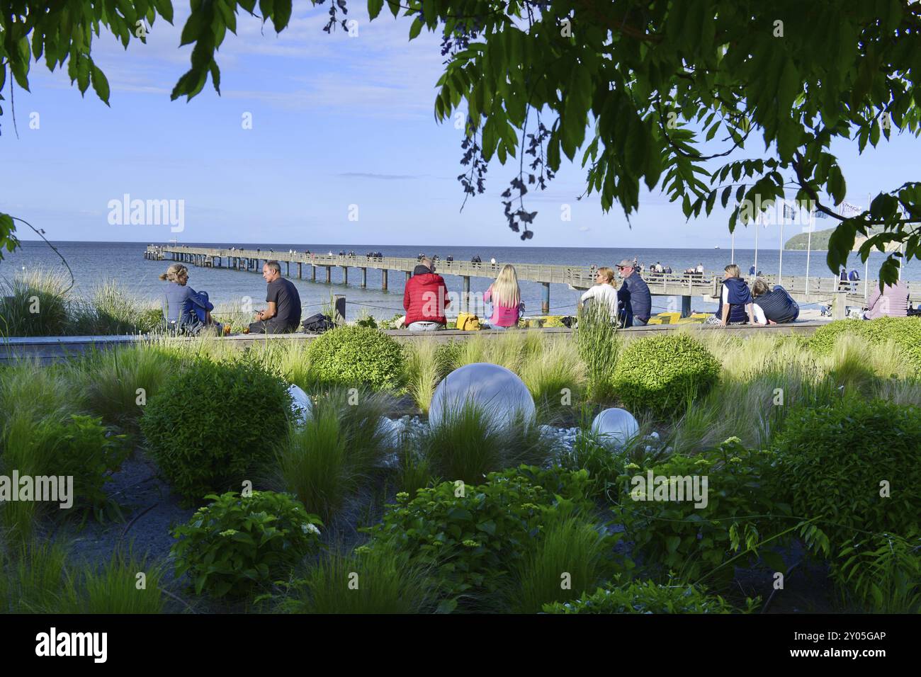 Menschen genießen ihre Zeit in einem grünen Park mit Blick auf einen Pier, Rügen (Binz 1) Stockfoto