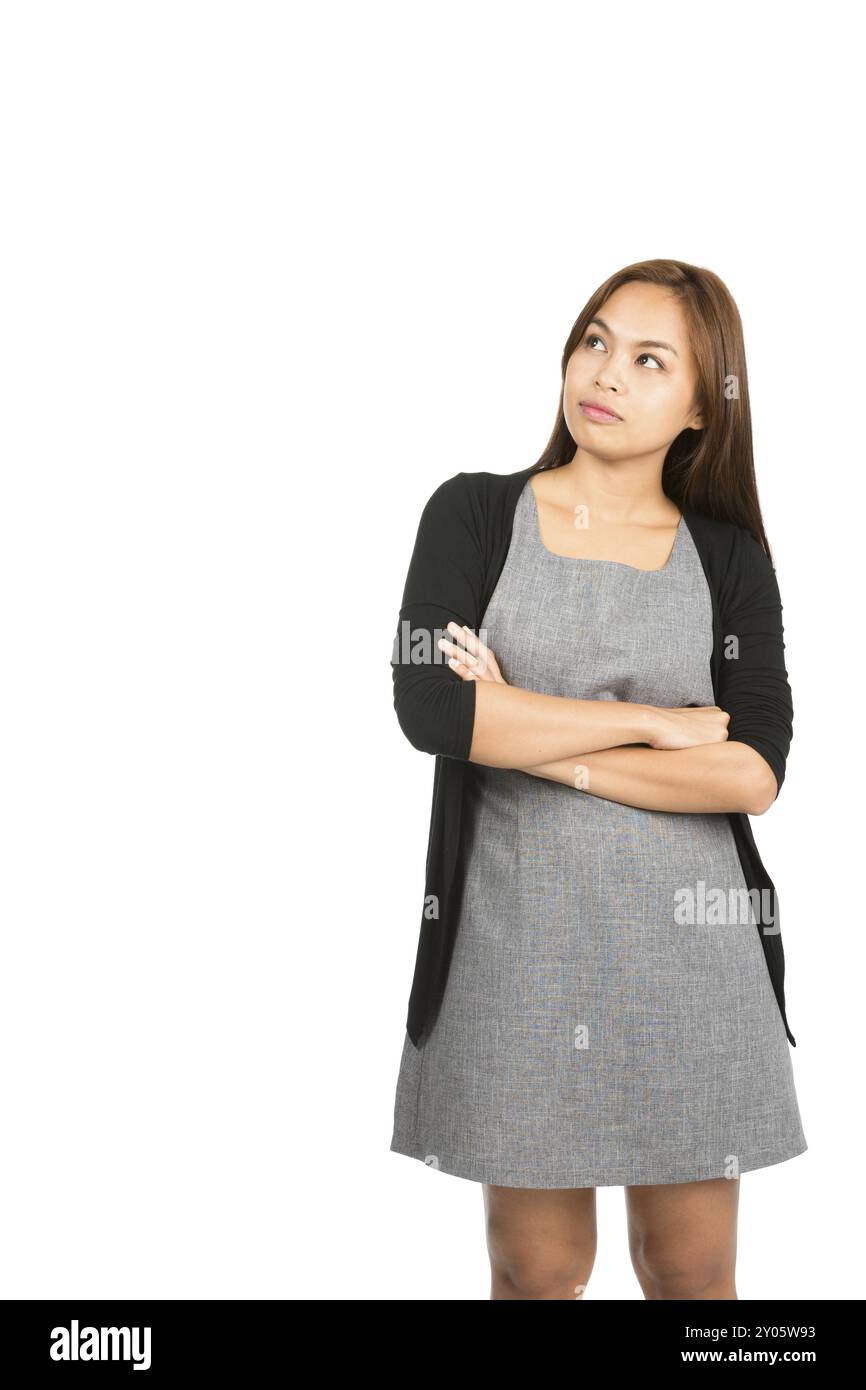 Eine nachdenkliche asiatische Frau, die Kleid trägt, einen Pullover mit ernstem, neugierigem Ausdruck, Arme überkreuzt, nachdenklich, mit Gedanken zum Kopierraum blickt, W Stockfoto