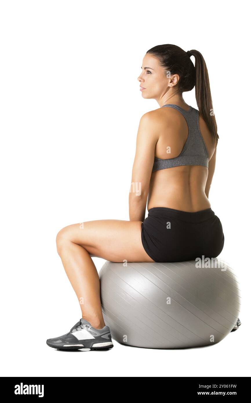 Fit Frau sitzt auf einer Yoga-Ball, isoliert in weiß Stockfoto