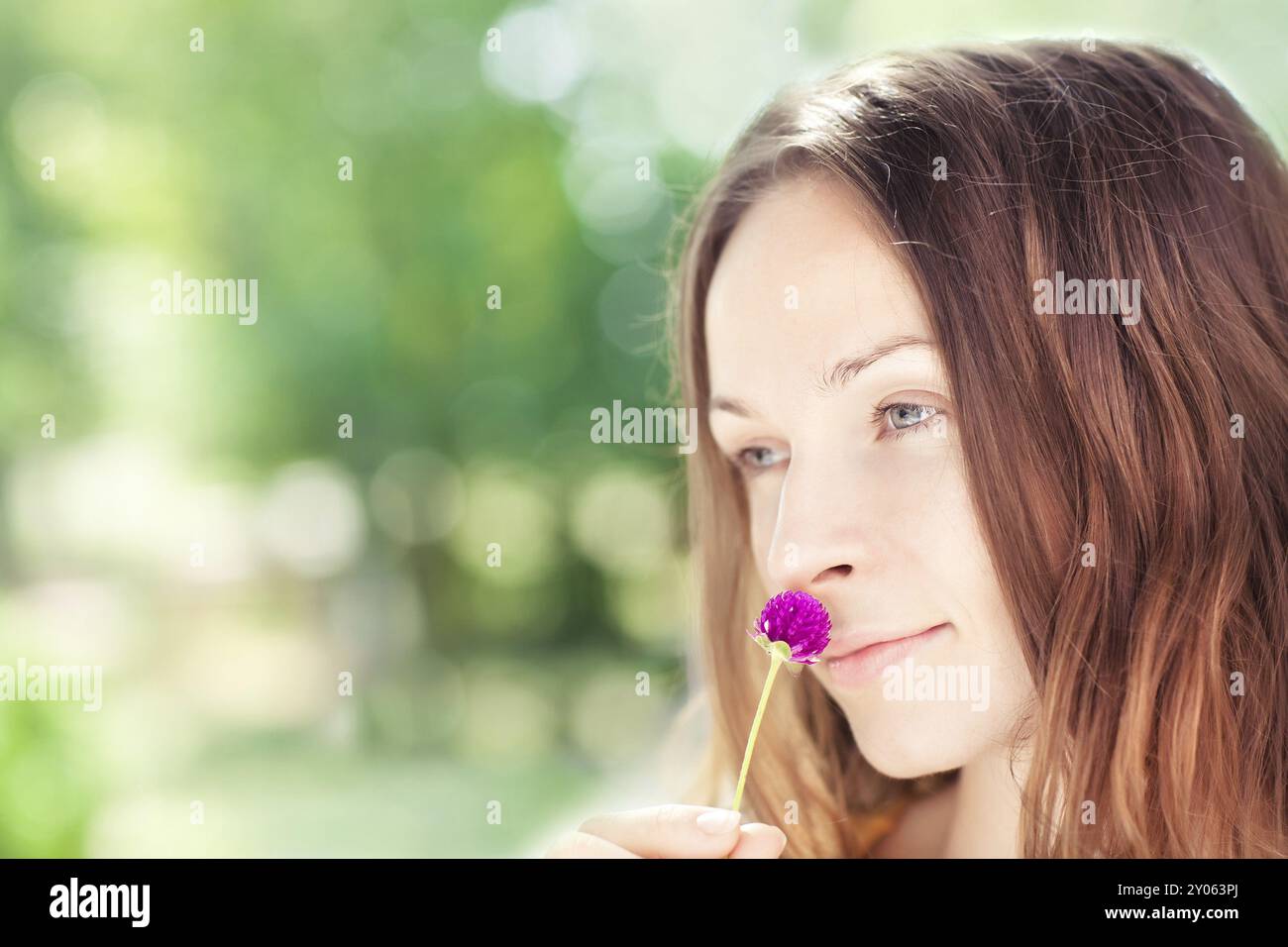 Porträt einer jungen Frau mit Blume im Sommerpark. Geringe Schärfentiefe Stockfoto