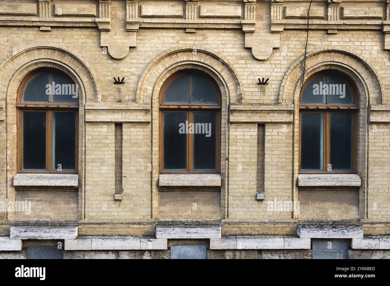 Drei alte Bogenfenster in einer Wand aus gelben Ziegeln. Grün, die Farben von Meereswellen-Glas in einem braunen dunkelroten Holzrahmen. Der Begriff des Antiken Stockfoto