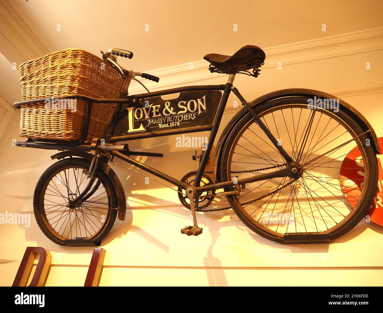 Love and Son Family Metzger traditionelles Metzgerrad mit Gepäckträger und Korb an der Wand montiert und im Chippenham Museum in Wilshire ausgestellt Stockfoto