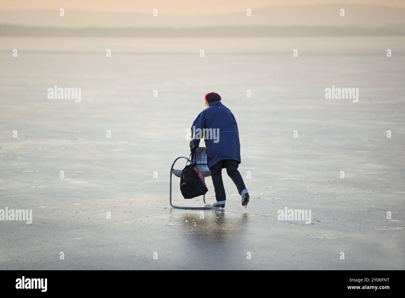 Ältere Frau mit einem Stuhl mit Läufern auf dem Eis, Steinhuder Meer, Niedersachsen Stockfoto