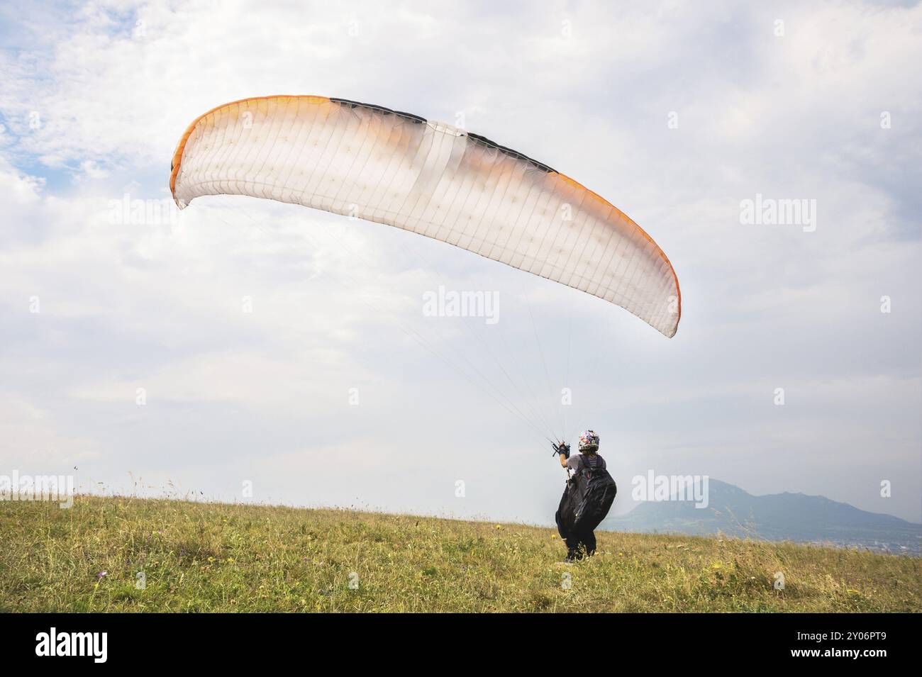 Der Gleitschirmflieger öffnet seinen Fallschirm, bevor er vom Berg im Nordkaukasus abhebt. Füllen Sie den Fallschirmflügel vor dem Start mit Luft Stockfoto