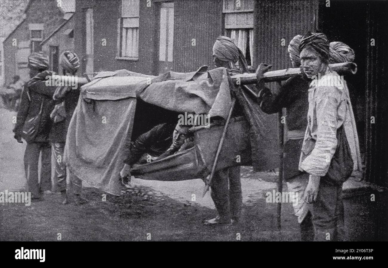 In einem ergreifenden Moment aus dem Burenkrieg transportieren indische Träger einen verwundeten Soldaten auf einer Dhoolie. Stockfoto