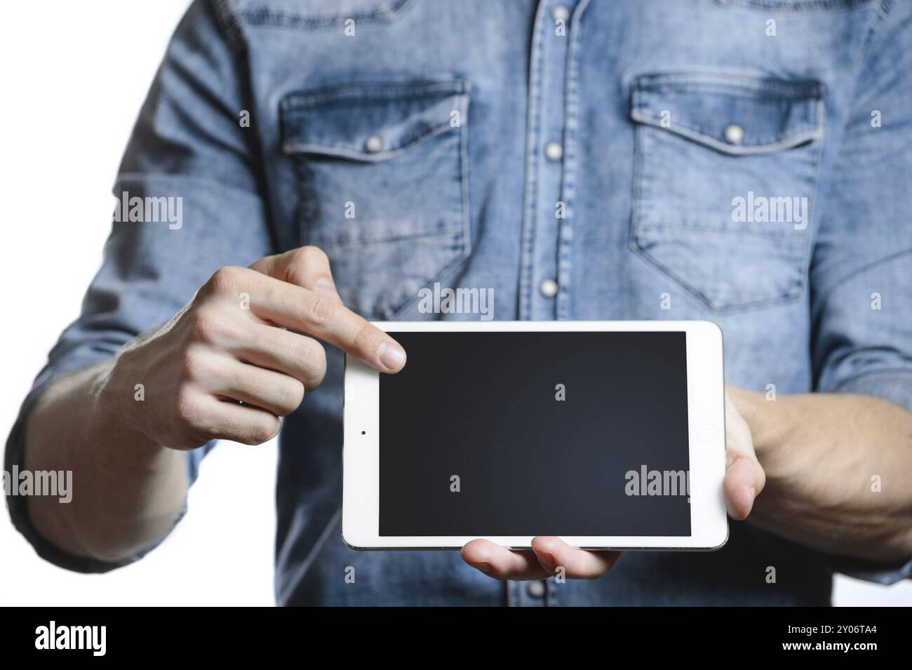 Lässiger Mann in Denim-Hemd, der digitalen Tablet-Computer-Bildschirm in den Händen zeigt. Isoliert auf weiß. Beschneidungspfad für die Anzeige enthalten. Er zeigt mit einem Finger A Stockfoto