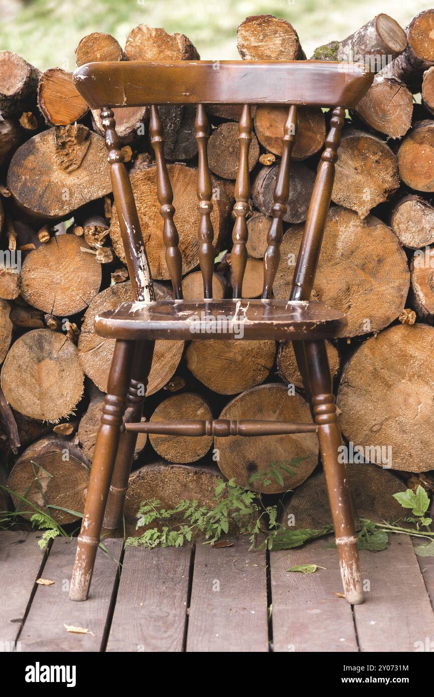 Alter Vintage Stuhl aus Holz auf dem Hintergrund von Holzscheite Brennholz Stockfoto