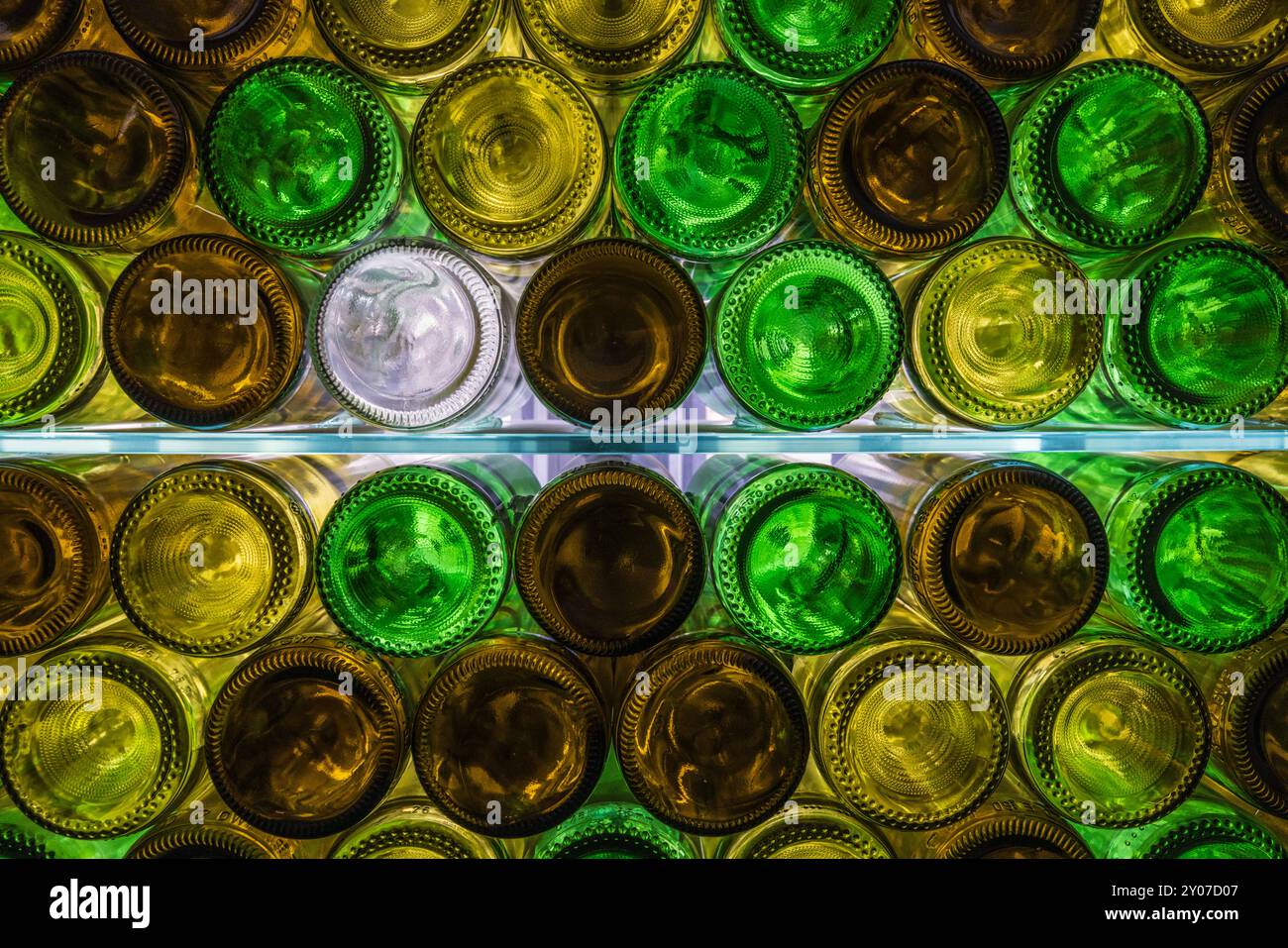 Natürlich beleuchtete, mehrfarbige Weinflaschen auf Glasregalen Stockfoto