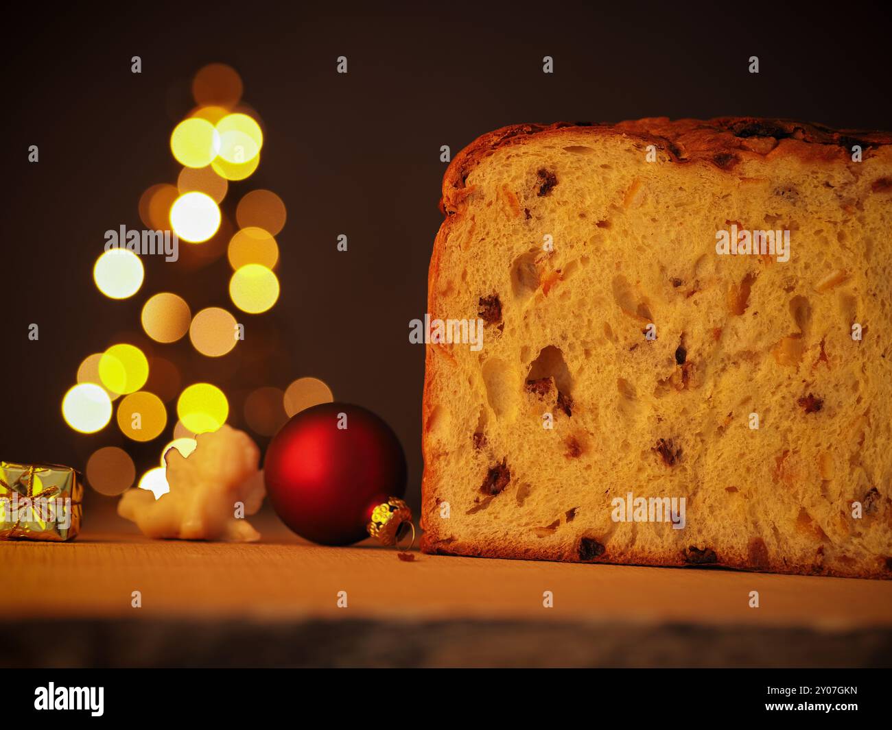 Die Hälfte der Panettone mit einem Weihnachtsbaum im Hintergrund Stockfoto