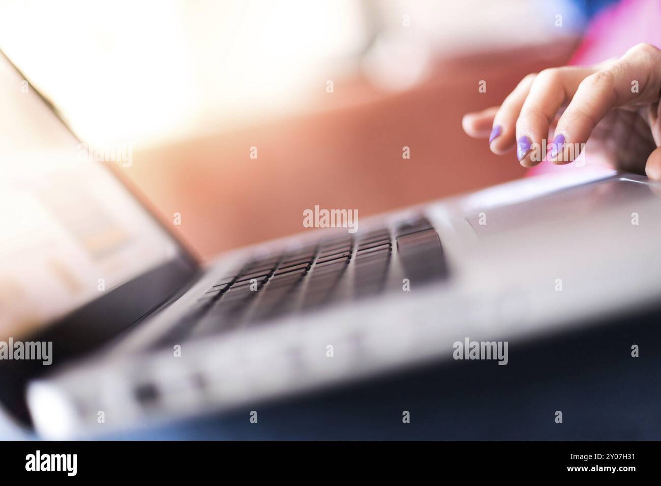 Mädchen mit violetten Fingernägeln benutzt ihren Laptop zu Hause auf der Couch Stockfoto