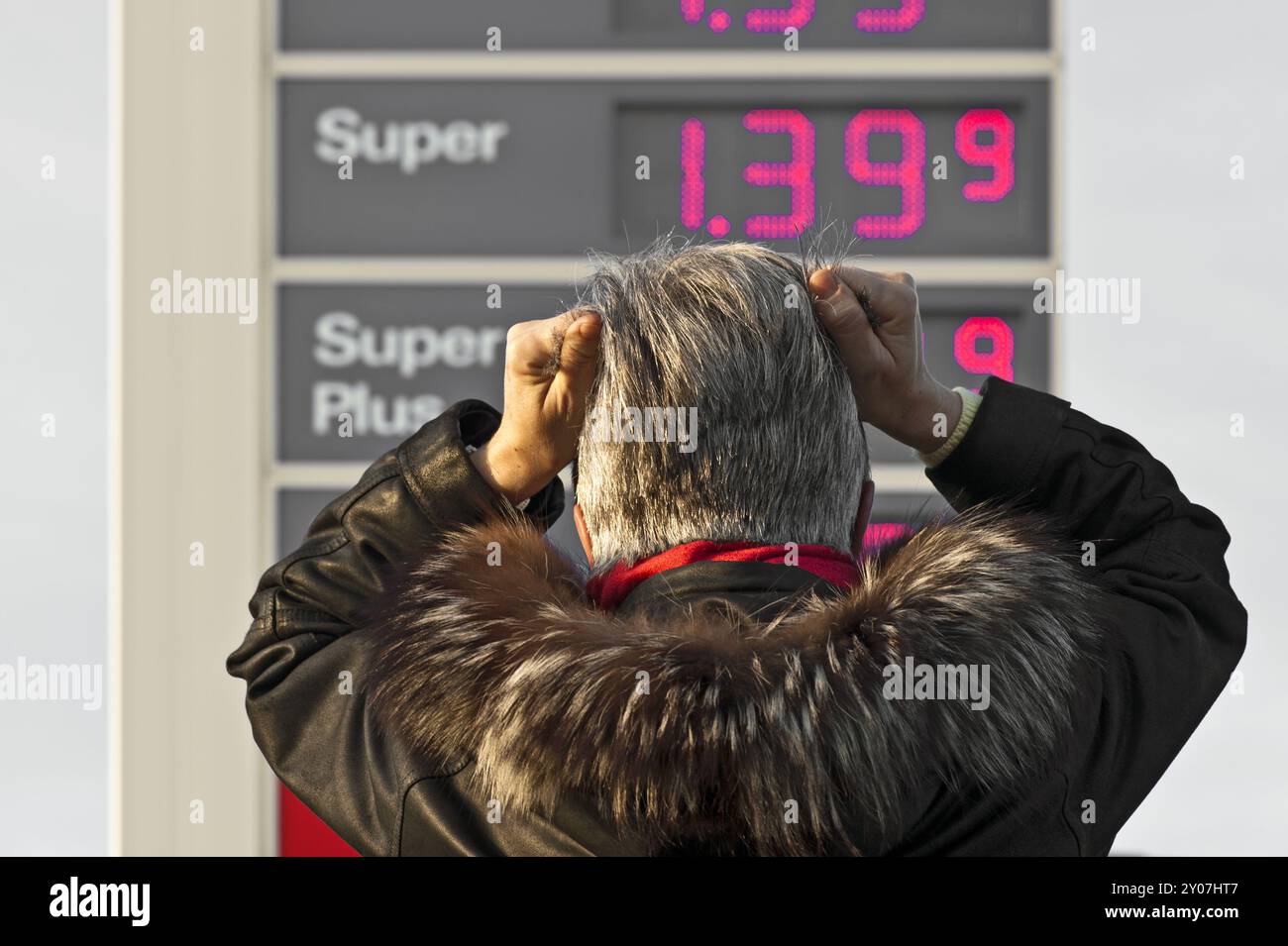 Frau, die vor der Preistafel einer Tankstelle steht Stockfoto