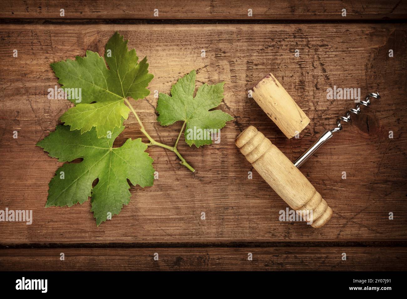 Ein Weinblatt mit einem Vintage Korkenzieher und ein Korken, Schuß von oben auf einen dunklen Holzmöbeln im Landhausstil Hintergrund Stockfoto