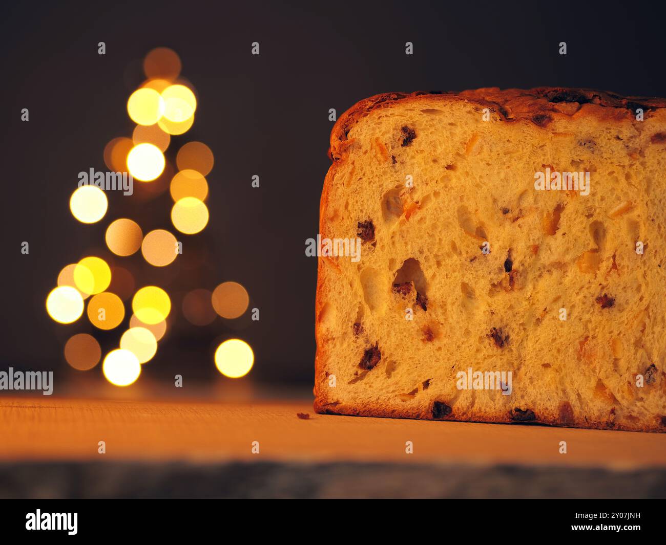 Die Hälfte der Panettone mit einem Weihnachtsbaum im Hintergrund Stockfoto