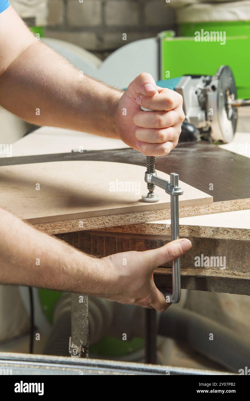 Close Up Master klemmt das Werkstück mit einer dvp-Klemme an der Werkbank und auf dem Hintergrund liegt der Handfräser von Carpentry Stockfoto