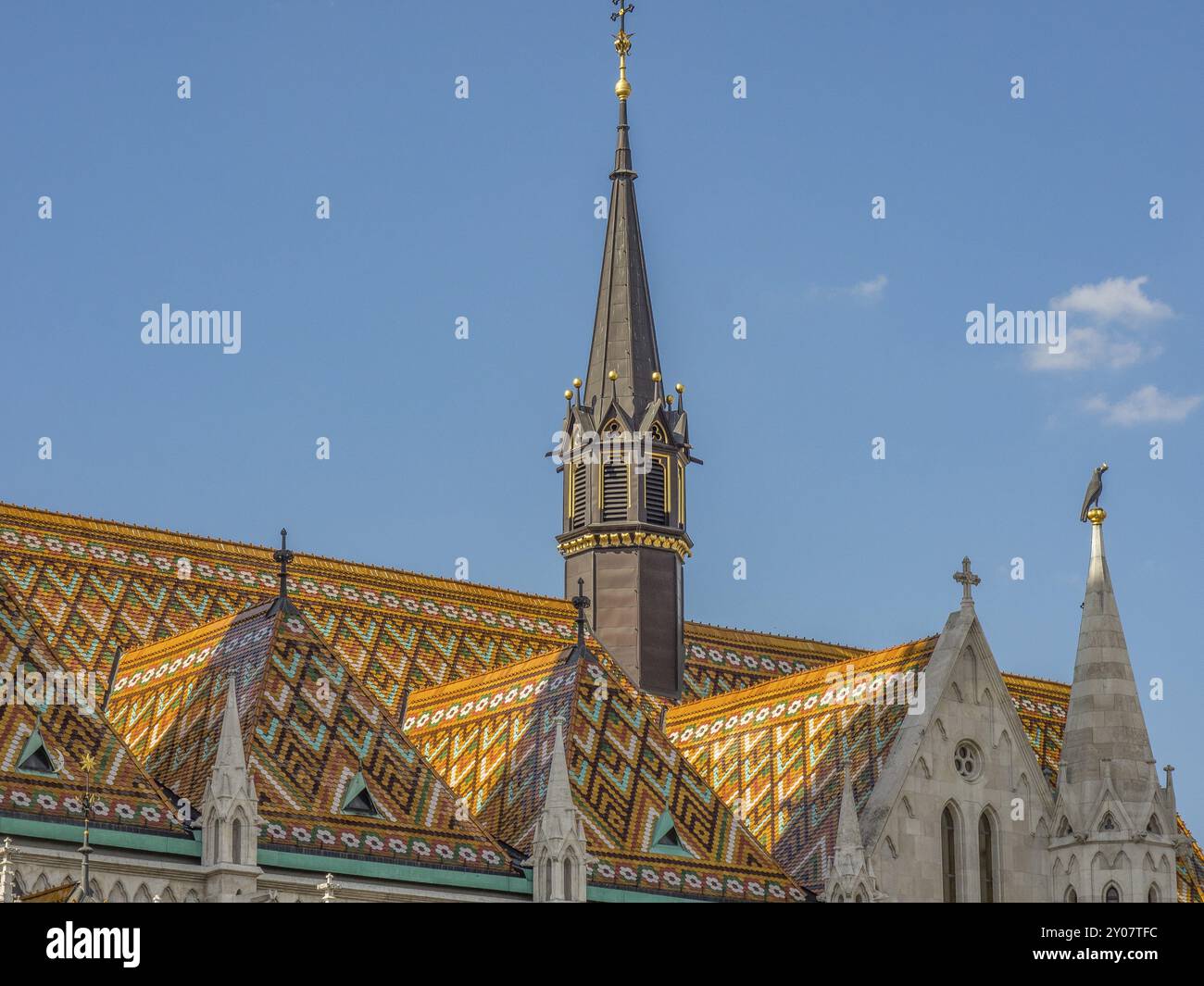 Kirchendach mit markantem Mustermosaik und gotischem Turm unter klarem, sonnigem Himmel, budapest, donau, ungarn Stockfoto