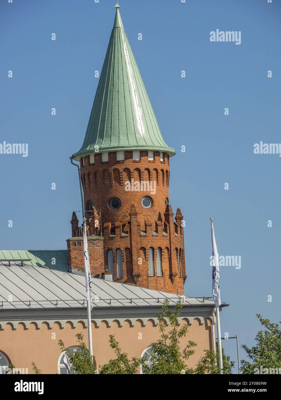 Roter Backsteinturm mit grünem Dach und Fahnen an einem sonnigen Tag, trelleborg, schweden, ostsee, skandinavien Stockfoto