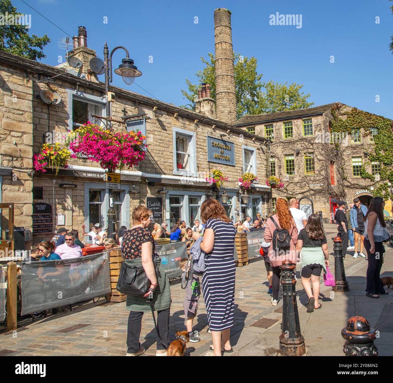 Die Leute genießen die Sommersonne in den Bars und Cafés in der Marktstadt Hebden Bridge in West Yorkshire im Calderdale Valley, England Stockfoto