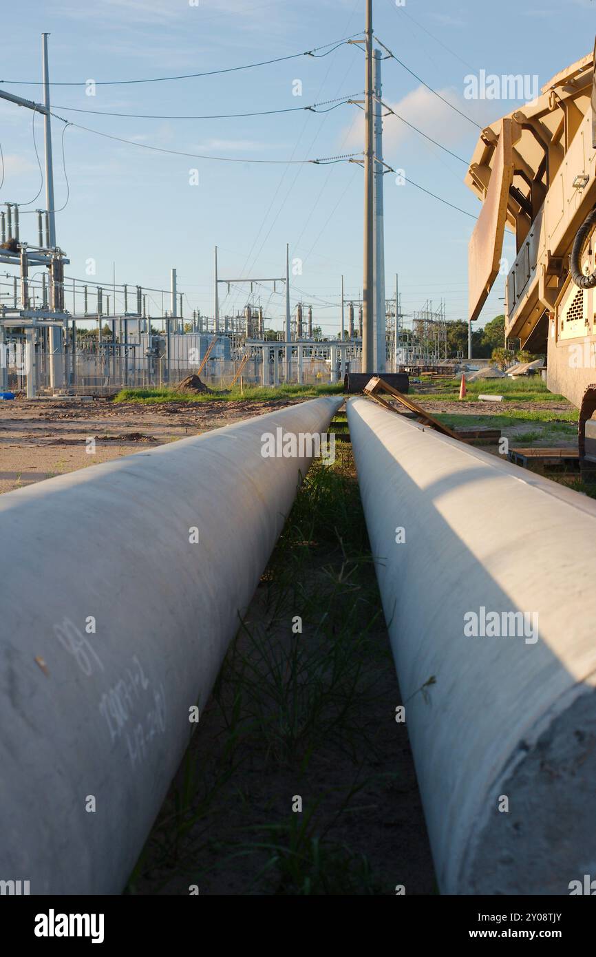 Niedrige senkrechte Leitlinie von zwei großen Metallmasten auf dem Boden. Gelbe Förderer-/Zuführungseinheit, Stapeleinheit rechts Stockfoto