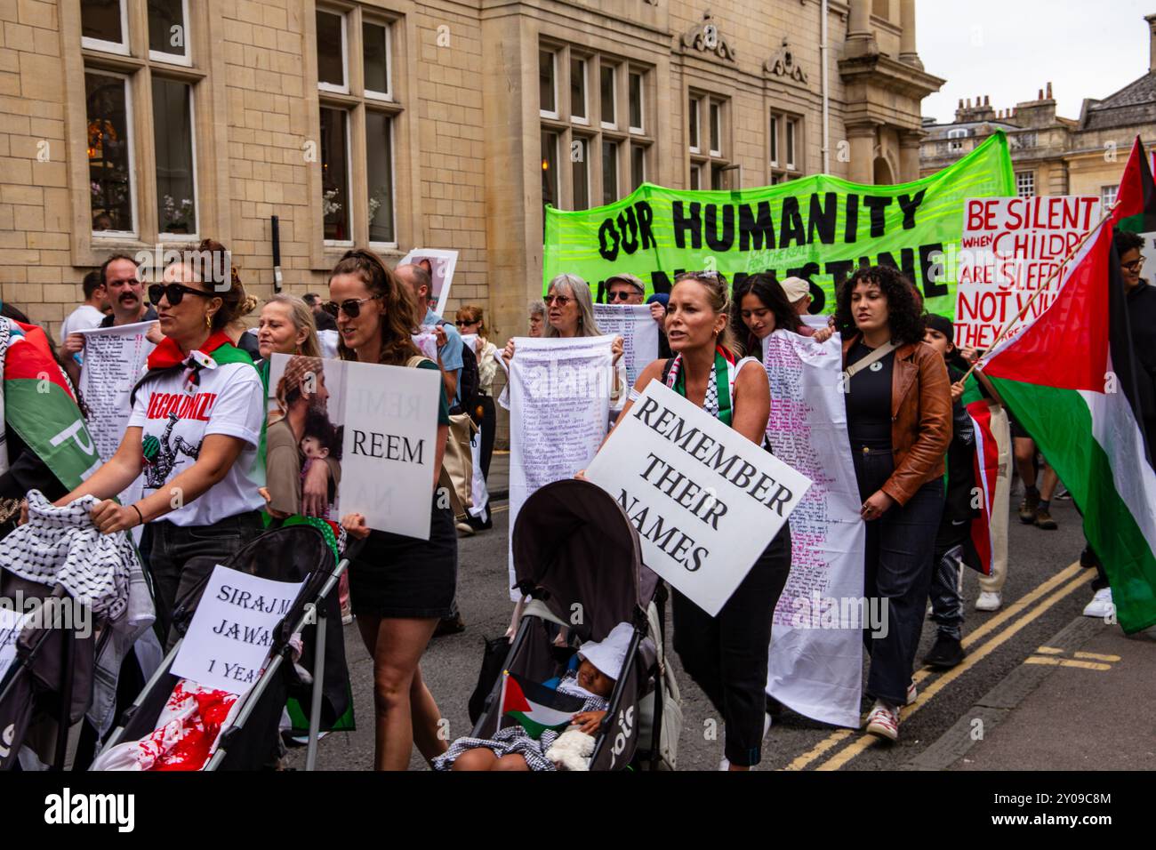 Eine Gruppe von Menschen, die während einer Demonstration in Bath England palästinensische Fahnen und Protestzeichen auf einer Straße halten Stockfoto