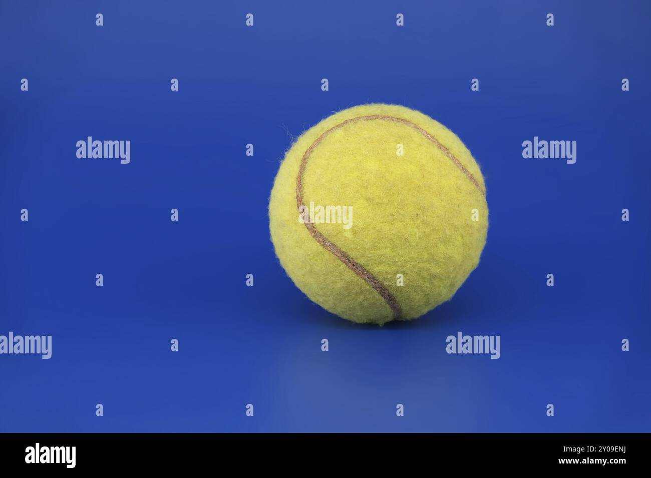 Gelber Tennisball auf hellblauem Hintergrund mit freiem Kopierraum in Nahansicht Stockfoto