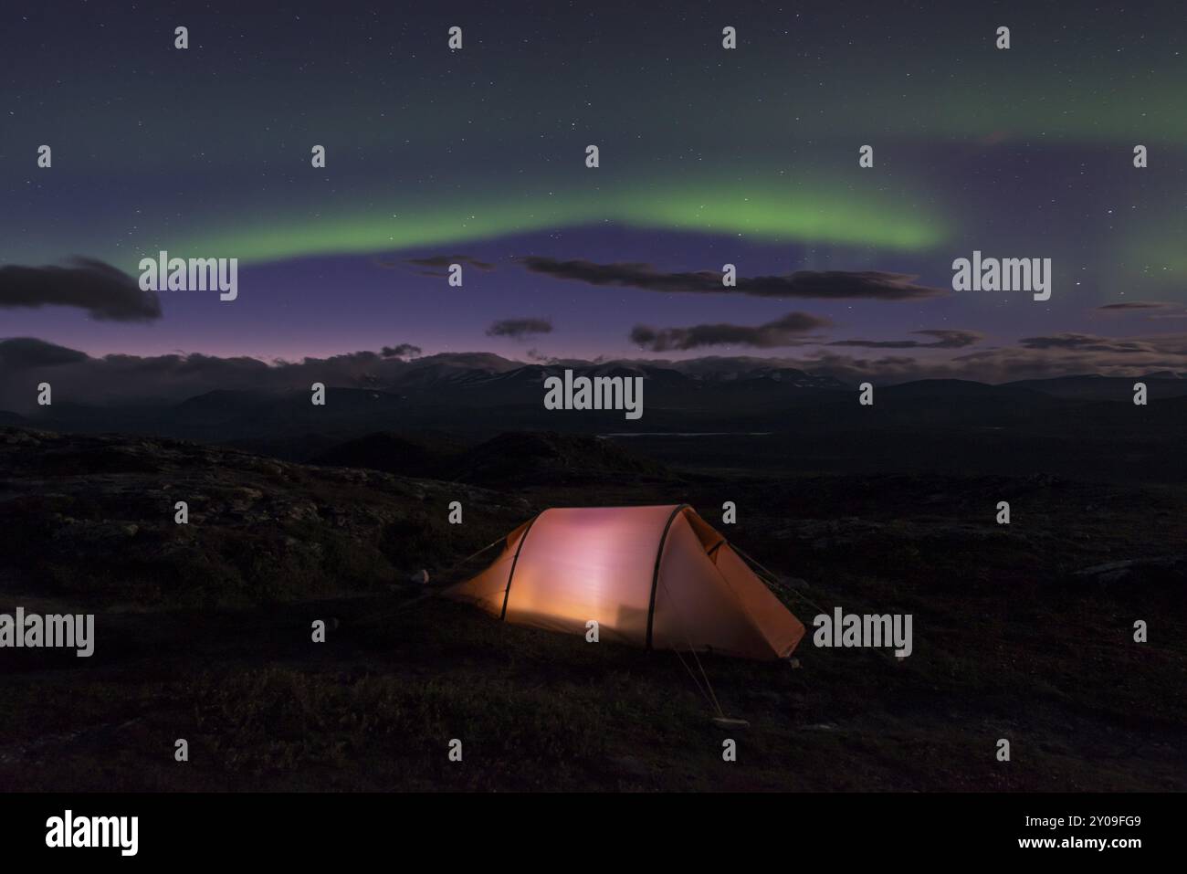 Nordlichter über beleuchtetem Zelt mit Blick auf Partemassiv, Sarek Nationalpark, Laponia, Norrbotten, Lappland, Schweden, September Stockfoto