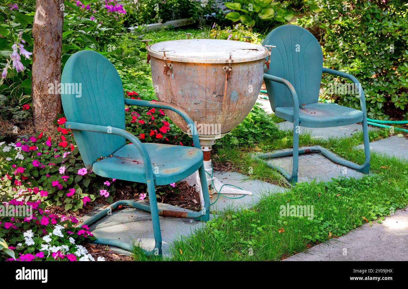 Die Inneneinrichtung im Freien besteht aus grünen Metallstühlen und einer alten, umgestalteten Paukentrommel (Wasserkocher drum), die als Beistelltisch verwendet wurde. Stockfoto