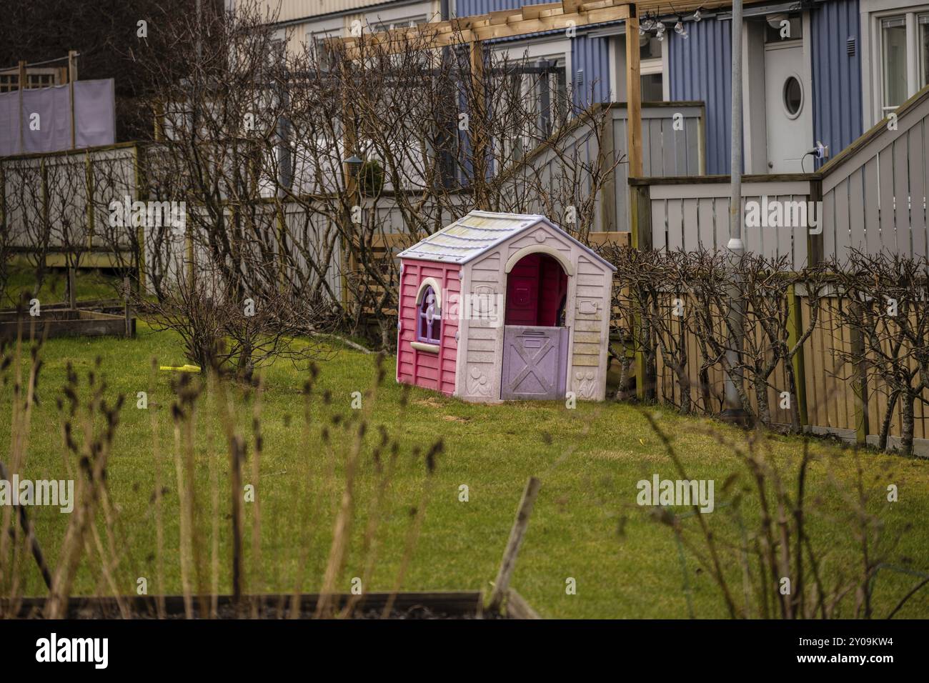 Pinkfarbene und violette Plastikspielhäuser in einem Garten Stockfoto