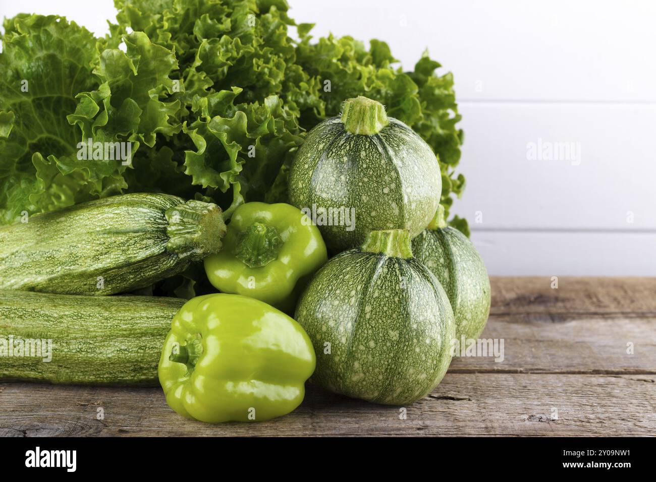 Mischung aus grünem Gemüse, Salat, Paprika, Zucchini auf hölzernem Hintergrund Stockfoto