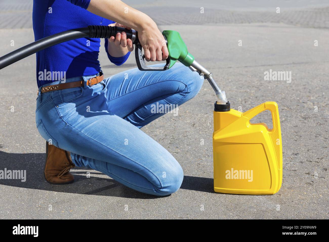 Frau Füllung gelb kann mit Benzin Schlauch im freien Stockfoto