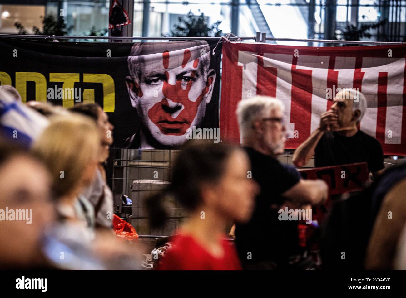 Während der Demonstration, bei der ein sofortiges Geiselabkommen und ein Waffenstillstand gefordert wird, gehen Demonstranten an einem Bild des israelischen Premierministers Benjamin Netanjahu vorbei. Israel sagt, dass seine Truppen die Leichen von sechs Geiseln, die von der Hamas im Gazastreifen festgehalten wurden, geborgen haben. In einer Erklärung sagten die israelischen Verteidigungskräfte (IDF), dass die Leichen am Samstag in einem unterirdischen Tunnel im Gebiet Rafah im südlichen Gazastreifen aufgefunden wurden. Die IDF nannte die Geiseln Carmel Gat, Eden Yerushalmi, Hersh Goldberg-Polin, Alexander Lobanov, Almog Sarusi und Meister Sgt Ori Danino. Stockfoto