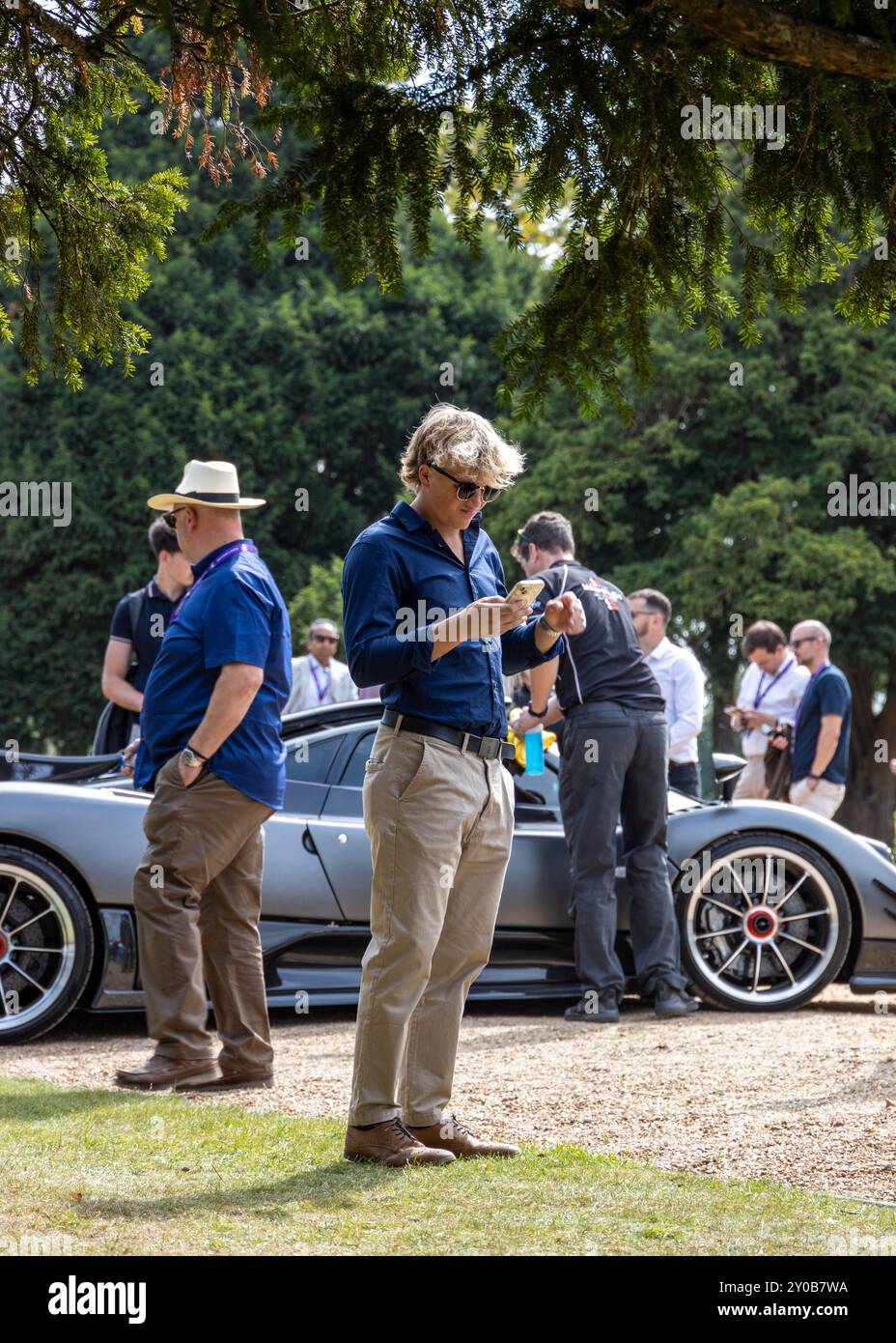 Ein Besucher nimmt sich einen Moment Zeit, um seine sozialen Medien auf dem Concours of Elegance 2024 zu überprüfen Stockfoto