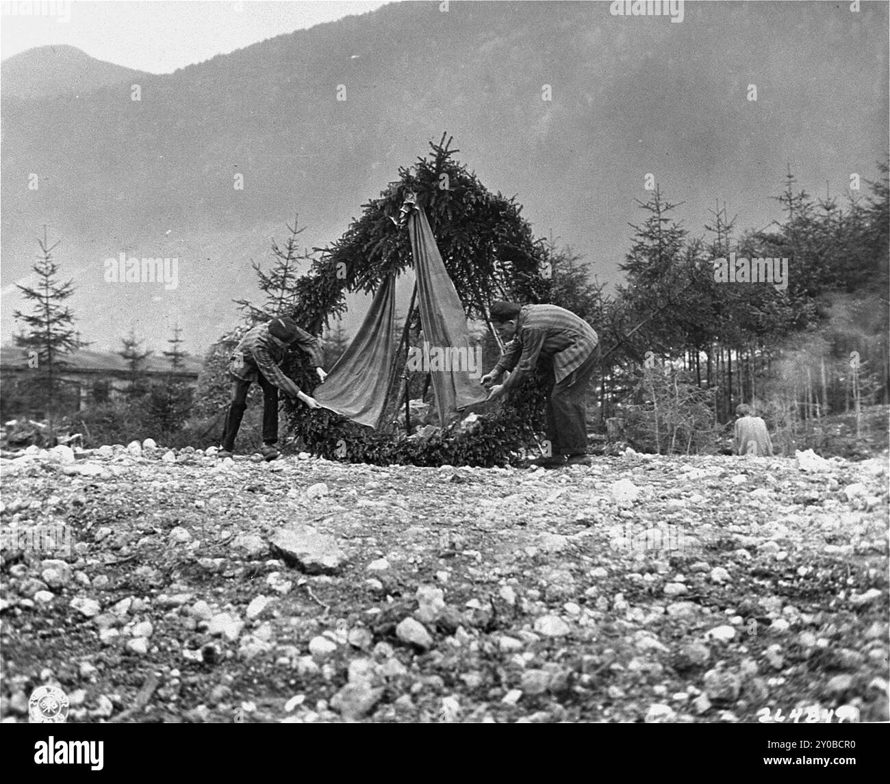 Überlebende legen einen Kranz an der Stelle eines Massengräbers im KZ Ebensee ab. Ebensee war ein Außenlager des Konzentrationslagers Mauthausen, das 1943 von der SS errichtet wurde, um Tunnel für die Rüstungslagerung in der Nähe der Stadt Ebensee zu bauen. Obwohl der Mauthausen-Komplex kein Vernichtungszentrum war, waren Grausamkeit und Vernachlässigung alltäglich. Zwischen 8.500 und 11.000 Gefangene starben im Lager, meist an Hunger oder Unterernährung. Die US-Armee befreite das Lager am 6. Mai 1945. Das Foto stammt vom 7. Mai 1945, einem Tag nach der Befreiung. Stockfoto