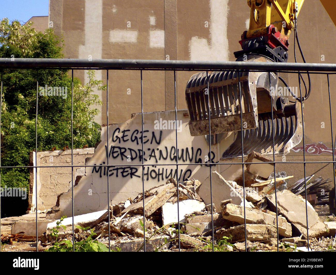 Der Bagger reißt die Wand mit Graffiti gegen Mieterhöhungen ein Stockfoto