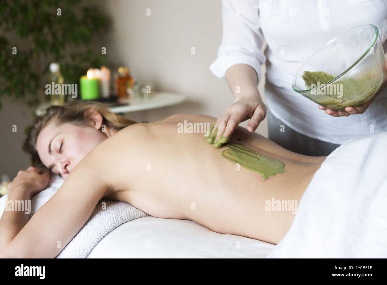 Schöne entspannte Frau in Clay Mask Anwendung durch die Kosmetikerin in der Spa Salon Stockfoto