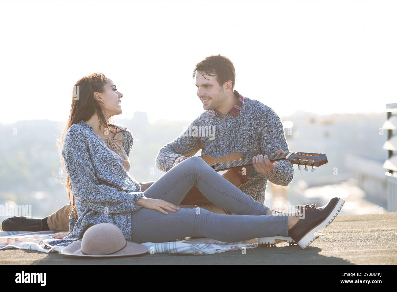 Junger Mann und Frau mit Gitarre, die Spaß im Freien haben Liebe und Beziehungen Konzept Stockfoto