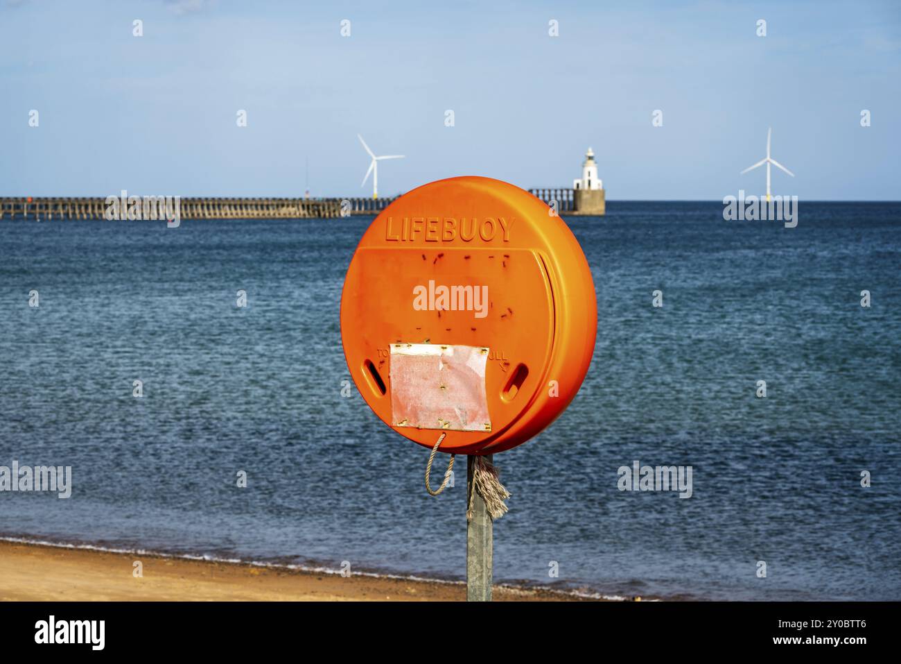 Ein Rettungsschwimmer an der Nordseeküste, gesehen am South Beach in Blyth, England, Großbritannien, mit Blyth Lighthouse und dem Pier im Hintergrund Stockfoto