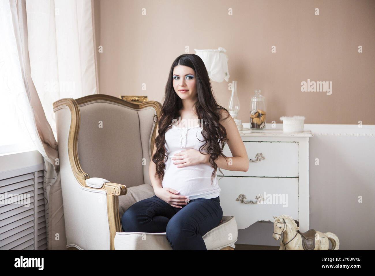 Ziemlich schwanger Frau im Sessel in gemütlichen Zimmer Stockfoto